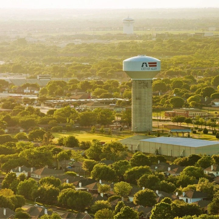 Aerial view of the Allen, TX water tower above tree-lined neighborhoods at sunset